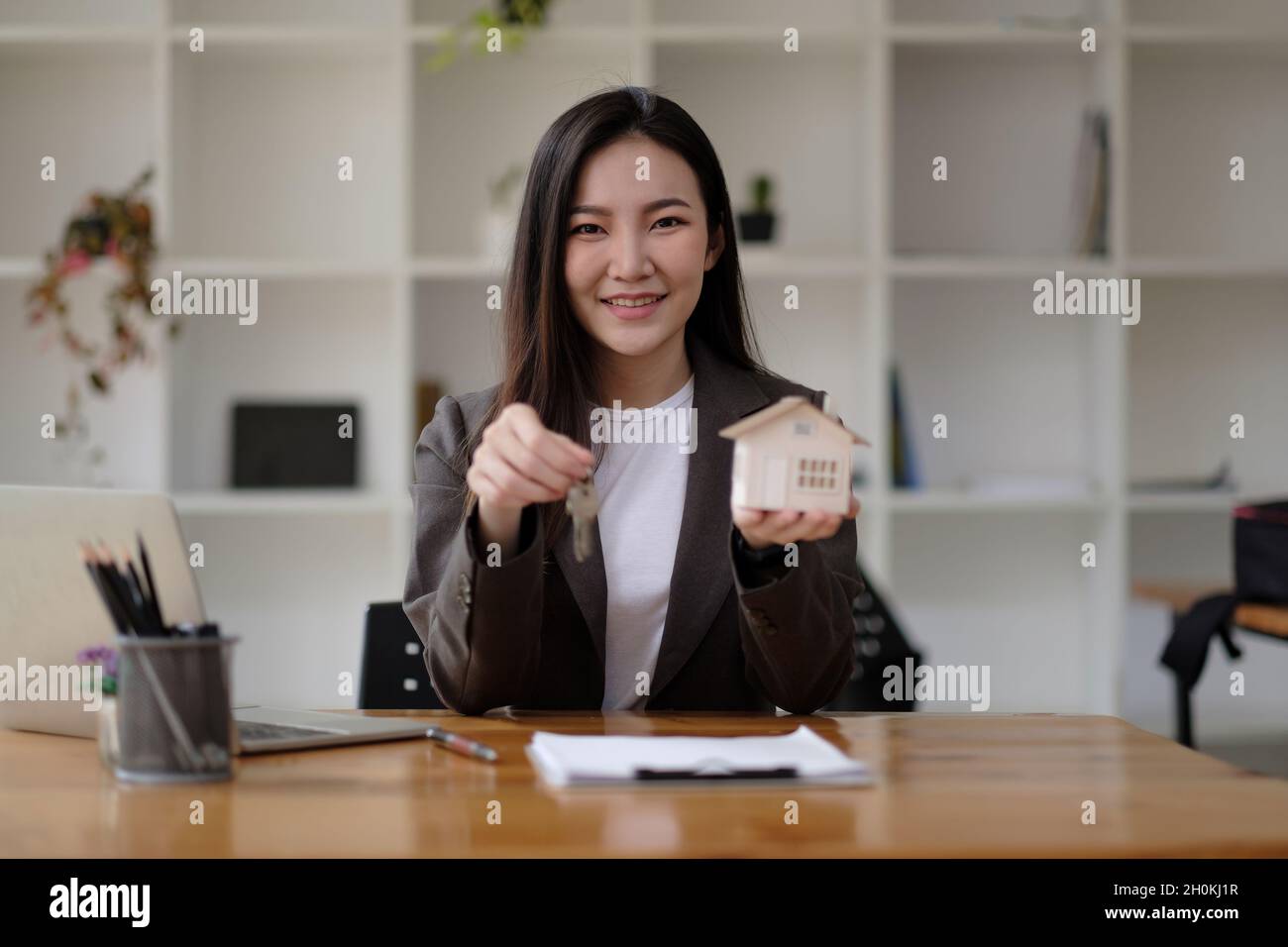 Real estate agent hand holding house model and keys Stock Photo - Alamy