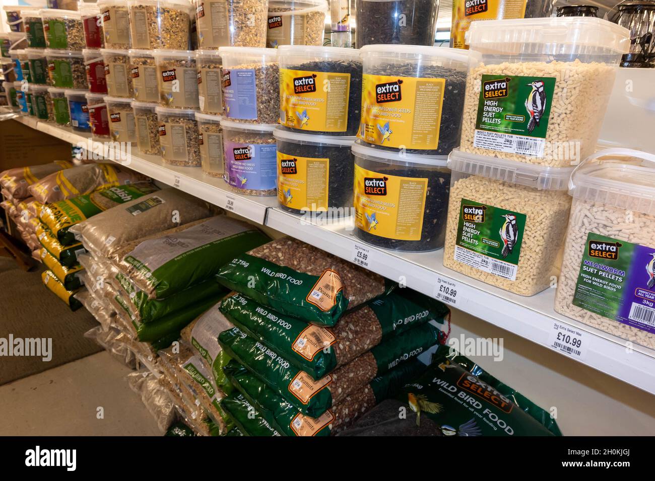 Large bags of wild bird food in sacks and tubs on a shelf in a