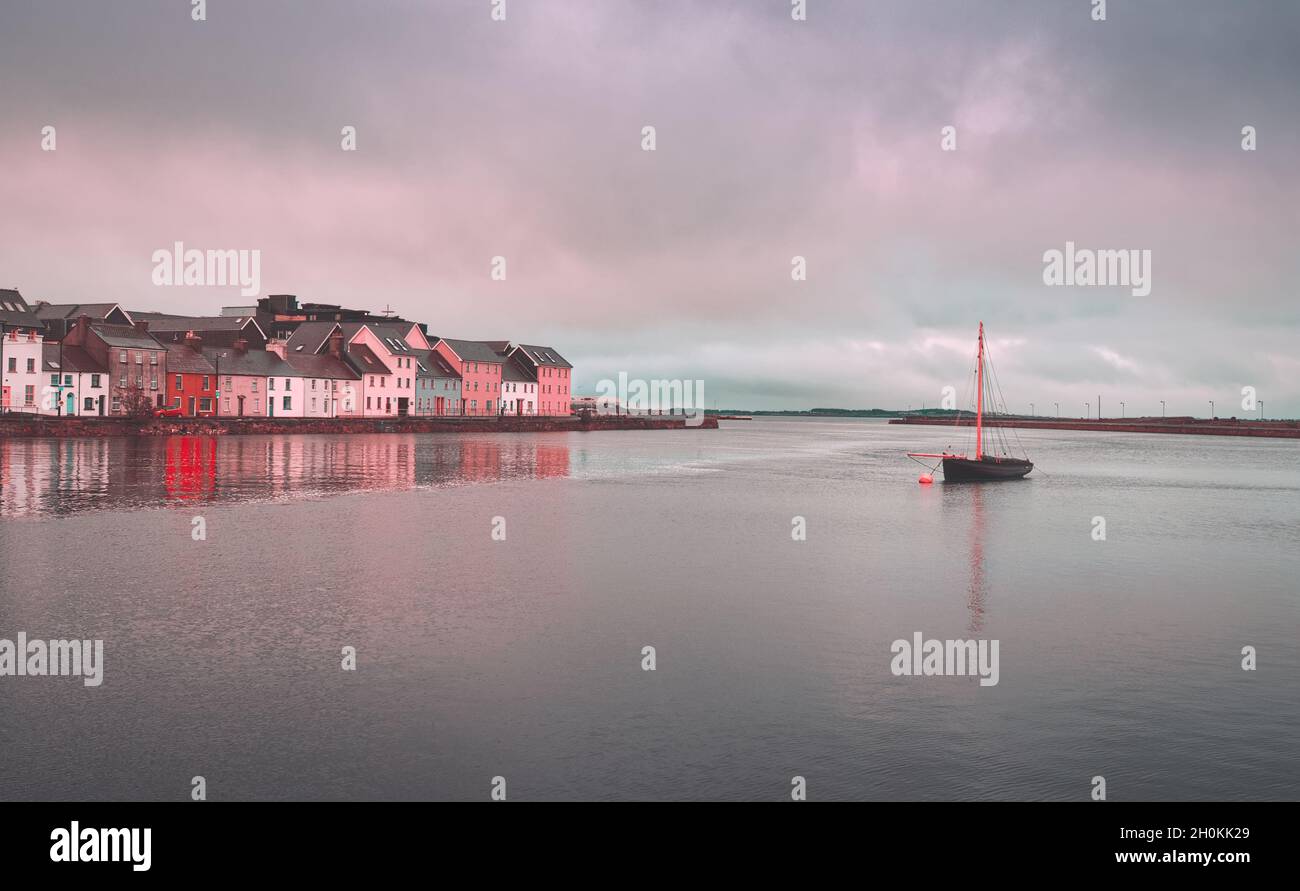 Beautiful cityscape scenery with old wooden fishing boat named Galway hooker in the Corrib River by the colorful houses in Galway city, Ireland Stock Photo