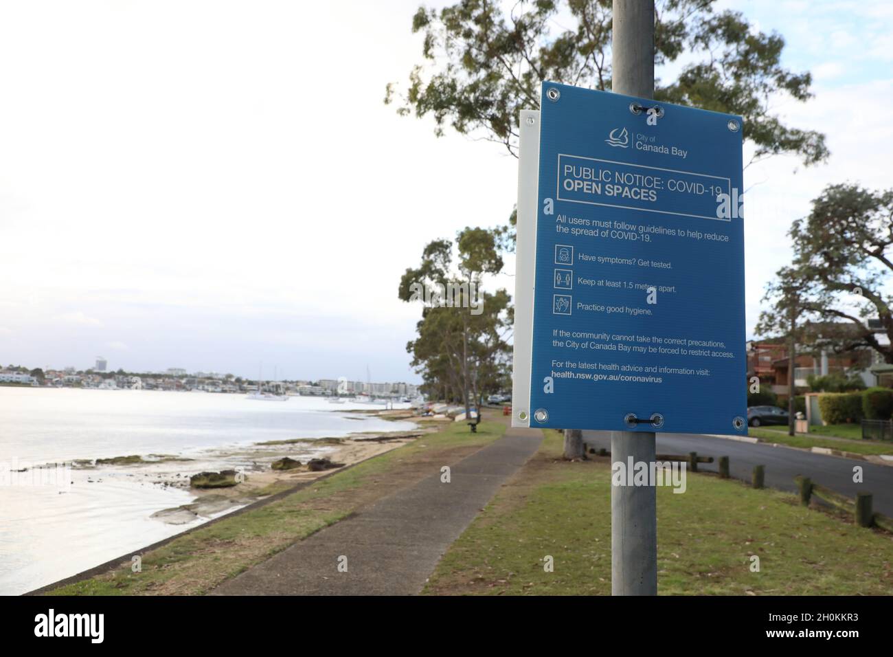 Sydney, Australia. 13th October 2021. Pictured: City of Canada Bay council Covid-19 sign next to the Parramatta River on Wymston Parade, Abbotsford. So called ‘freedom day’ was on 11th October as places in New South Wales open up only to the vaccinated and a system of segregation and apartheid is introduced. About 75% of the population who are fully vaccinated will be allowed inside various venues, but the other 25% who are not fully vaccinated with two doses are kept out. Credit: Richard Milnes/Alamy Live News Stock Photo