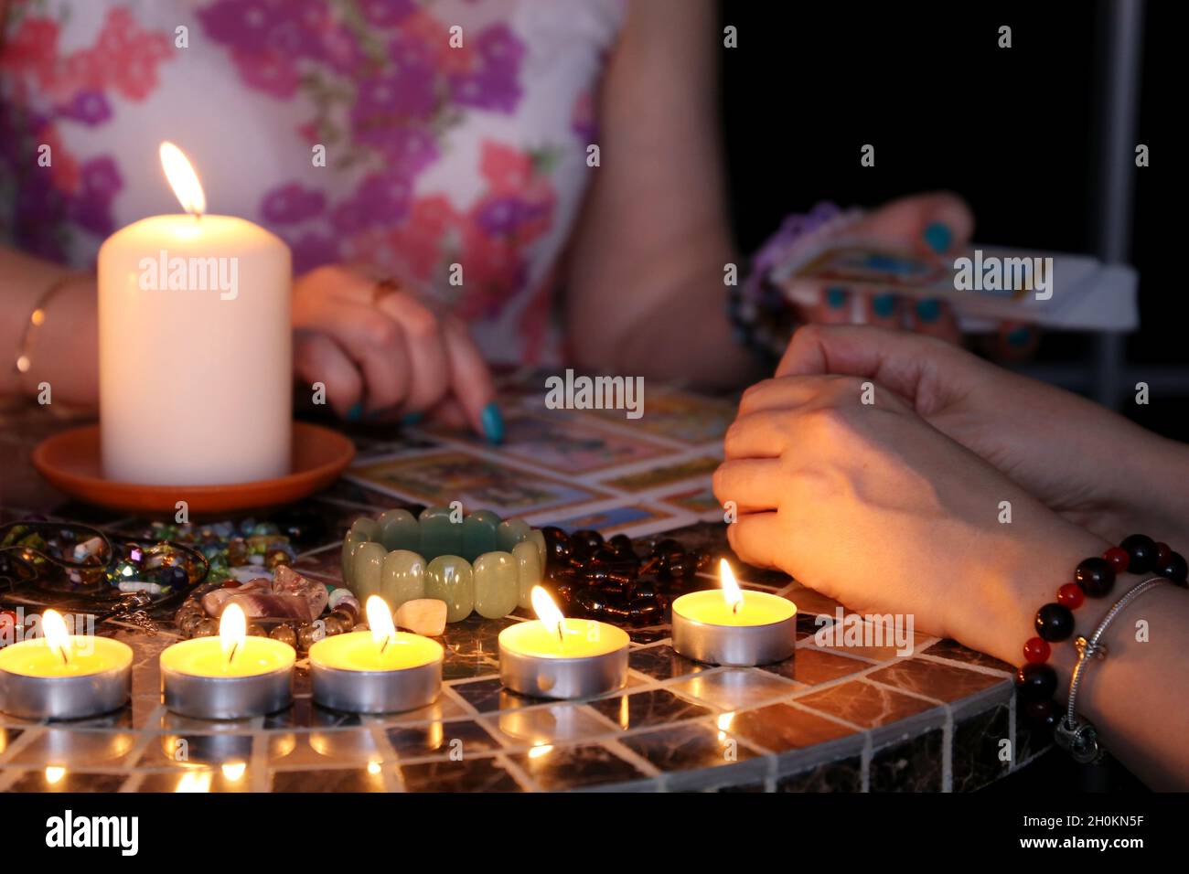 Fortune telling session, seeing the destiny and astrology. Female foreteller with woman client, tarot cards and candles on the round table Stock Photo