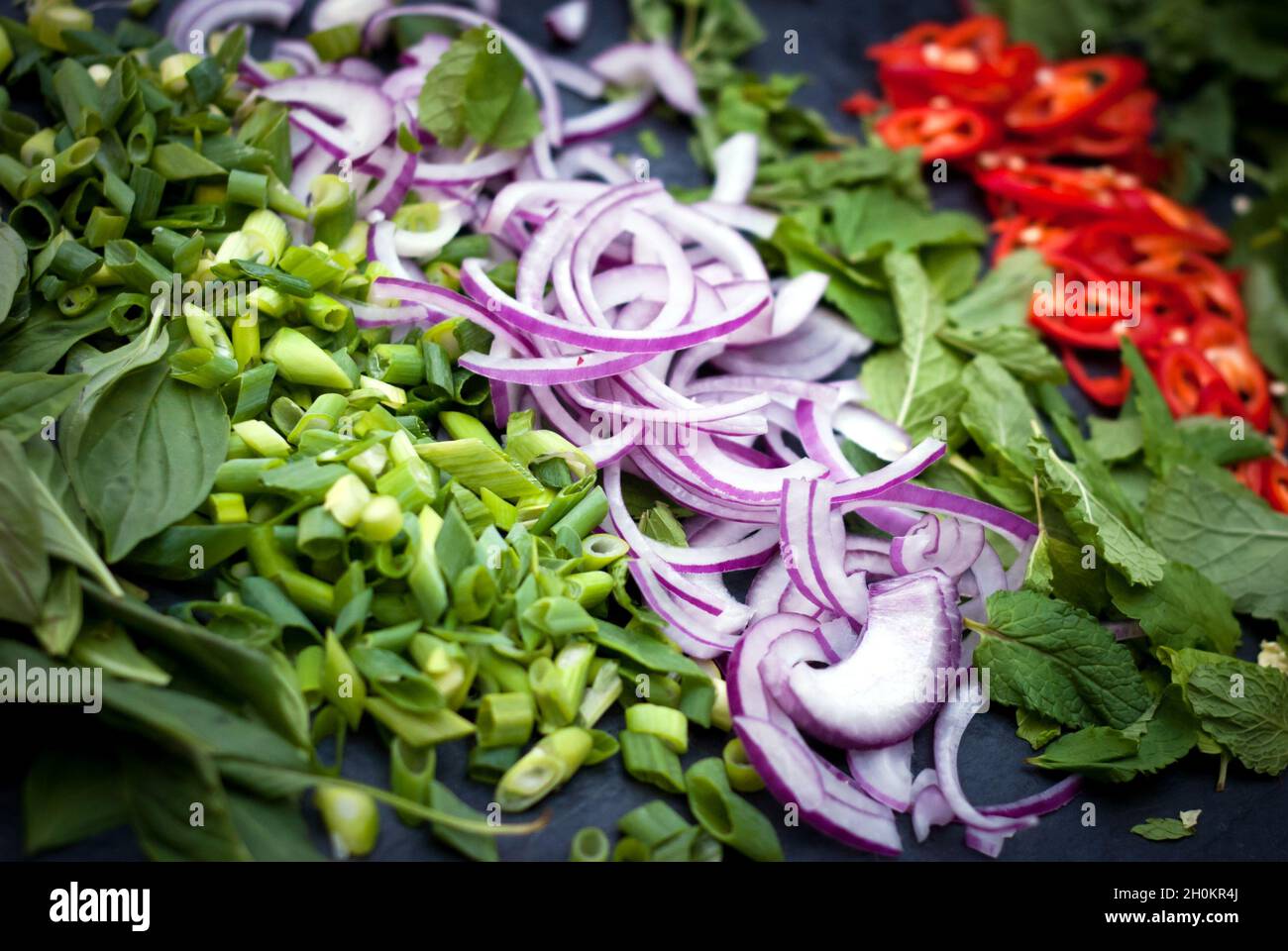 Herbs and vegetables preparation for South-East Asian cuisine: chilli, mint, basil, red onion, spring onions. Stock Photo