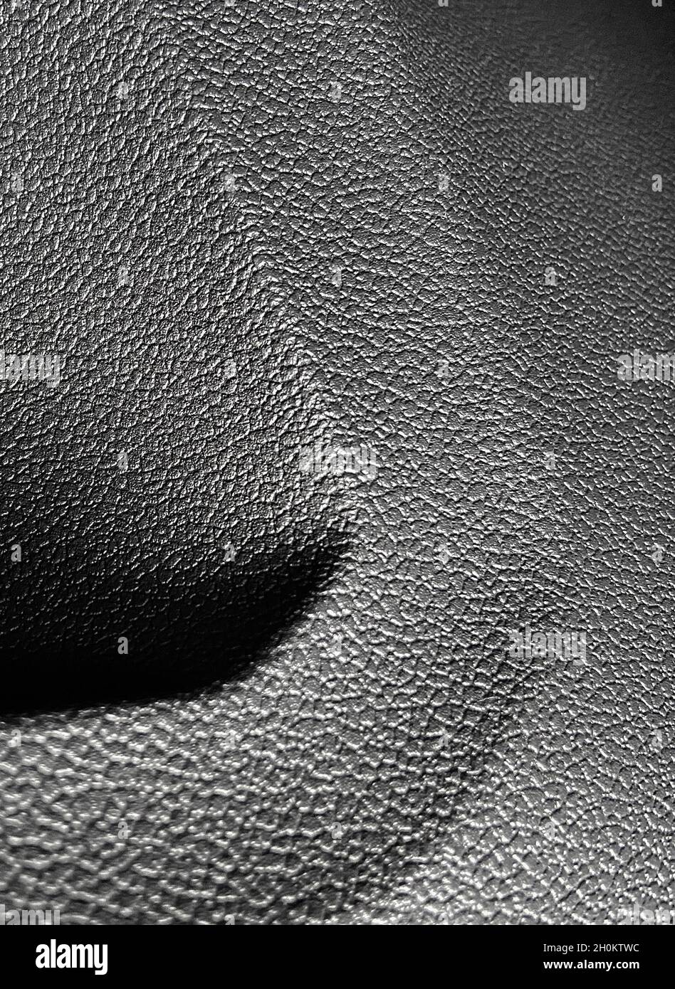 Closeup of the bumpy patterned gray plastic surface of a car’s door