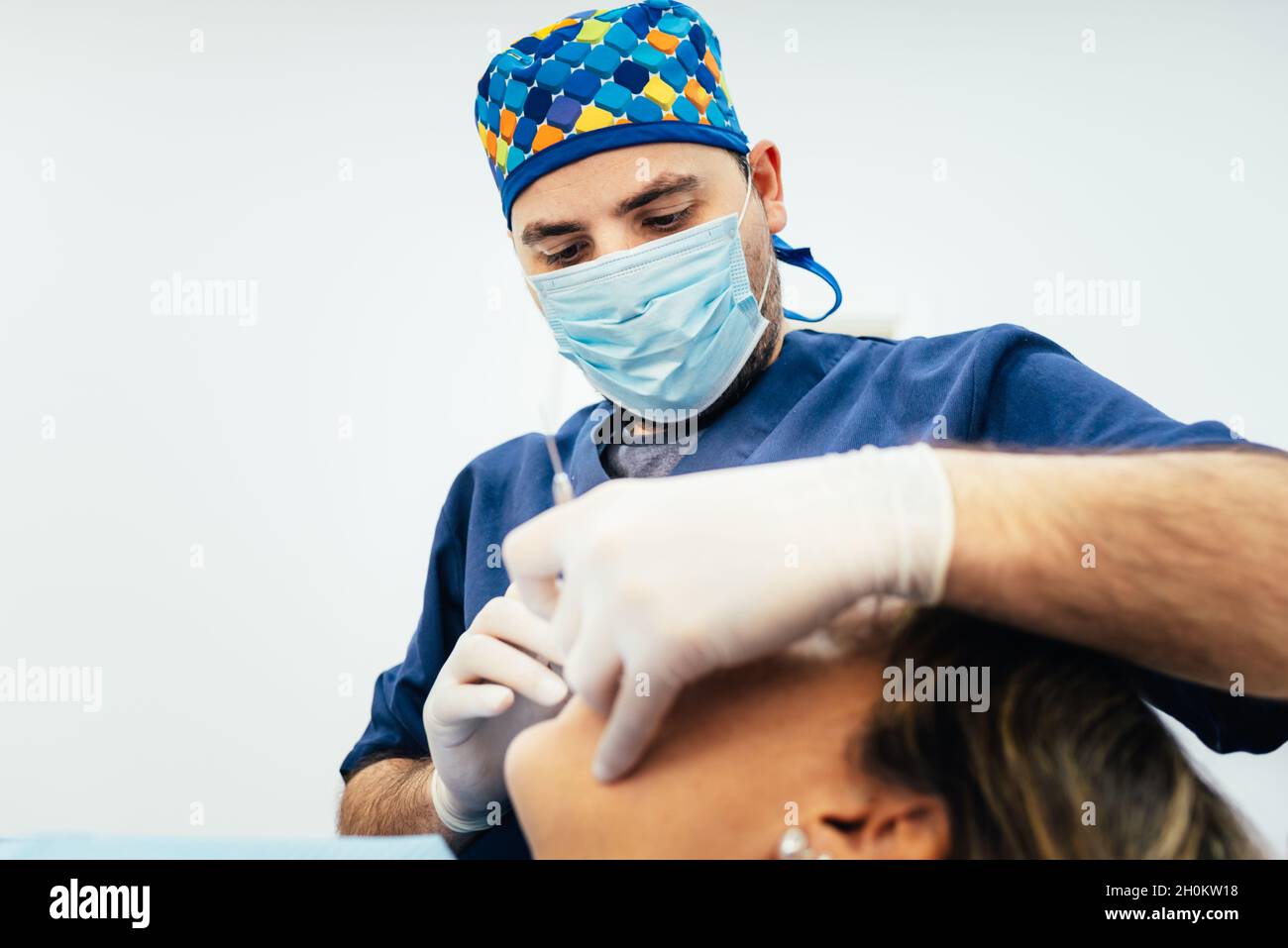 Professional male dentist wearing mask and gloves while treating a