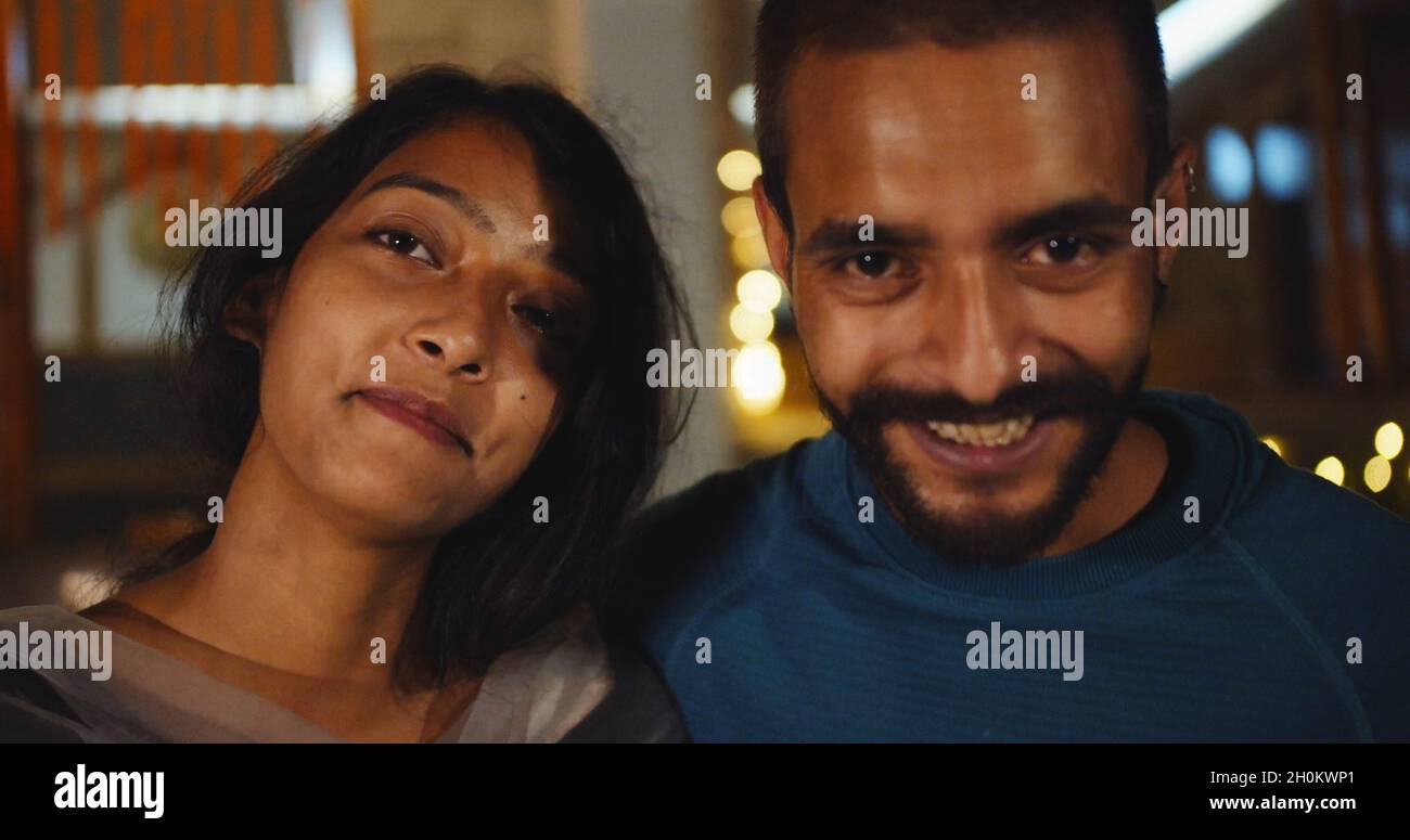Portrait of a beautiful young Indian couple smiling while looking at ...