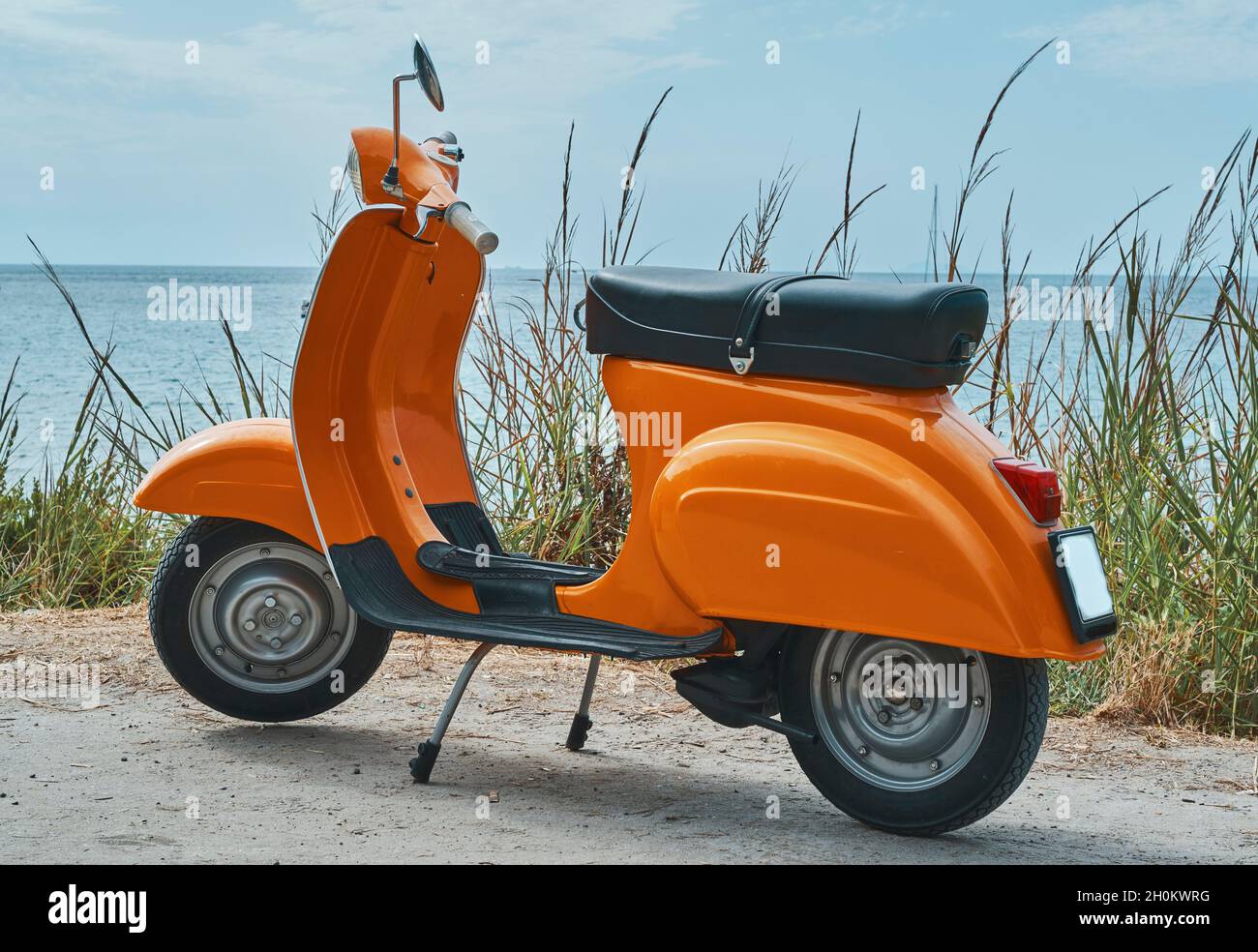 Vintage orange scooter parking on the beach. Stock Photo