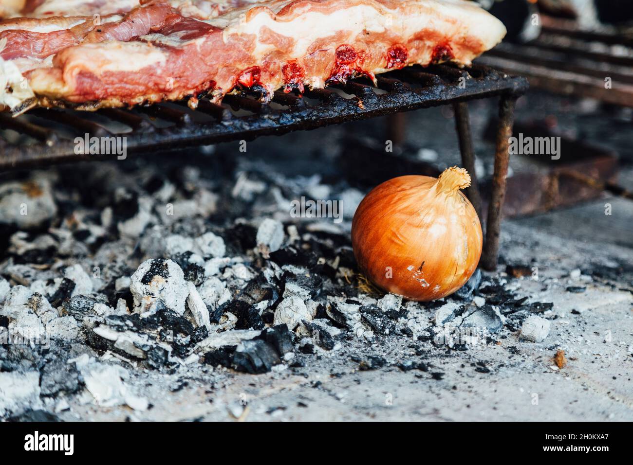 Onion over embers in the fireplace of traditional argentinian grill. Making asado in Argentina at the weekend. Stock Photo