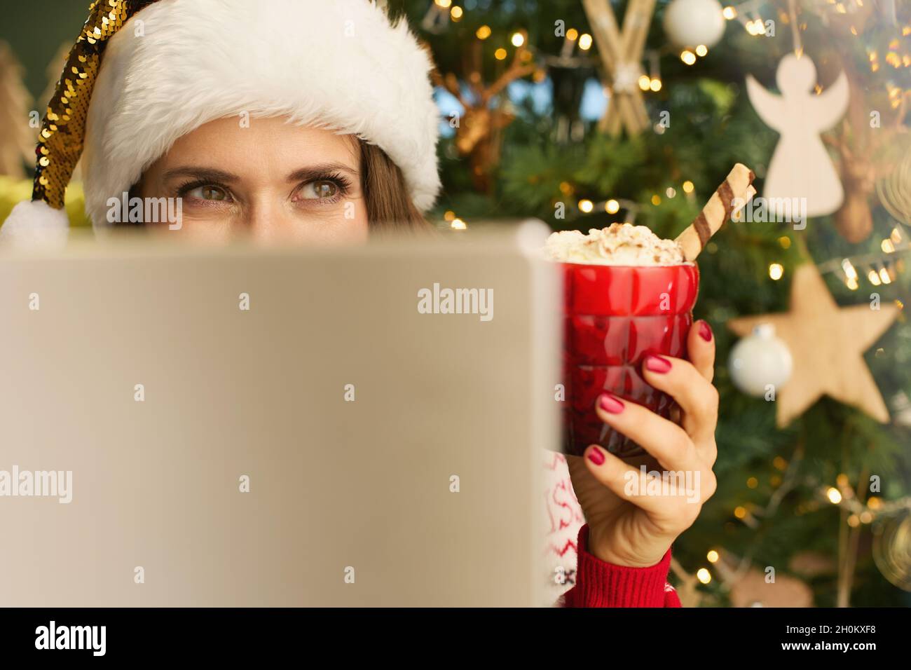 https://c8.alamy.com/comp/2H0KXF8/christmas-time-pensive-modern-middle-aged-housewife-with-santa-hat-and-festive-hot-chocolate-cocktail-making-online-shopping-on-e-commerce-website-on-2H0KXF8.jpg