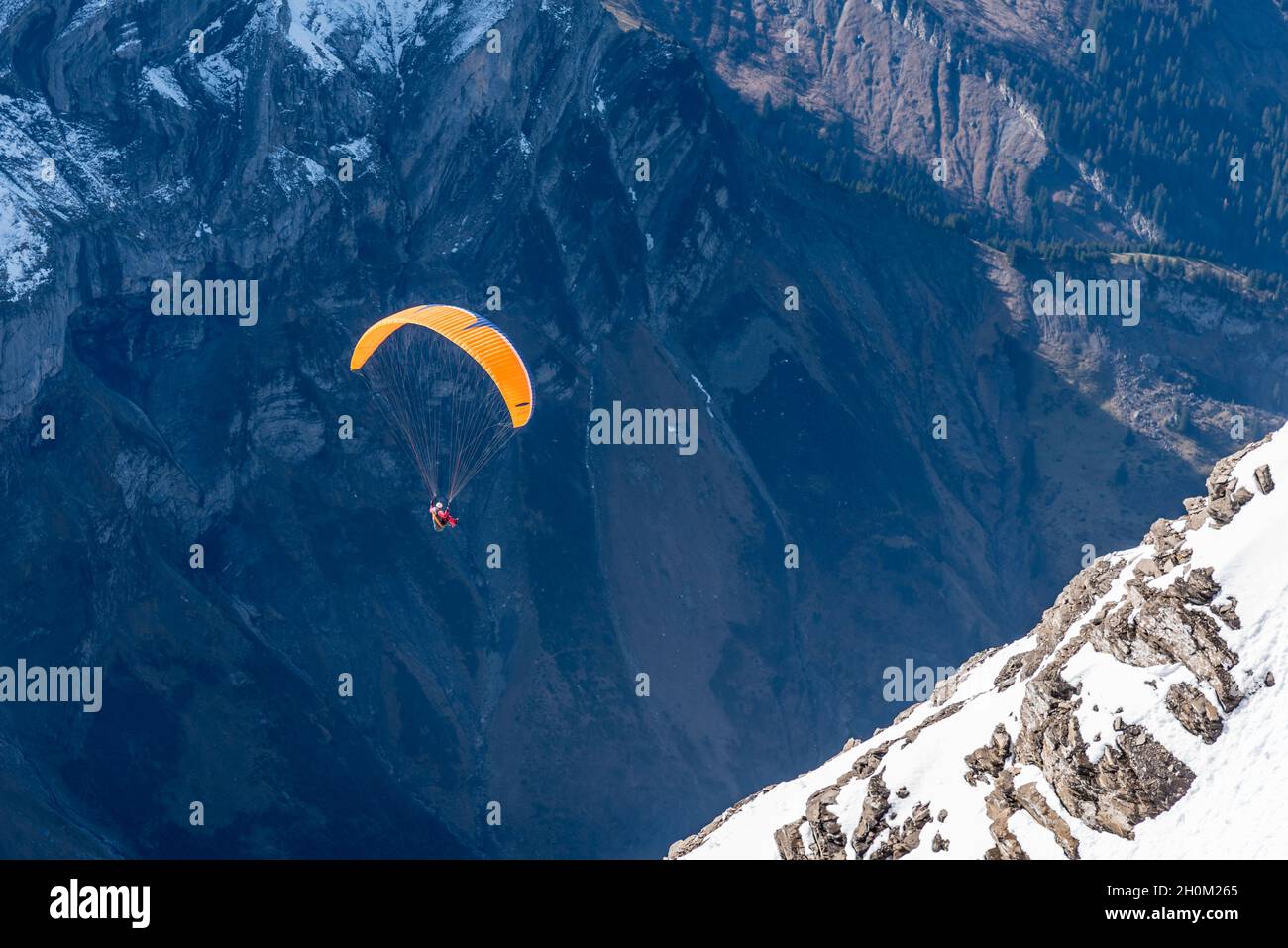 A person doing paragliding over the Diablerets glacier at 3000 meters above sea level in Switzerland in a winter day Stock Photo