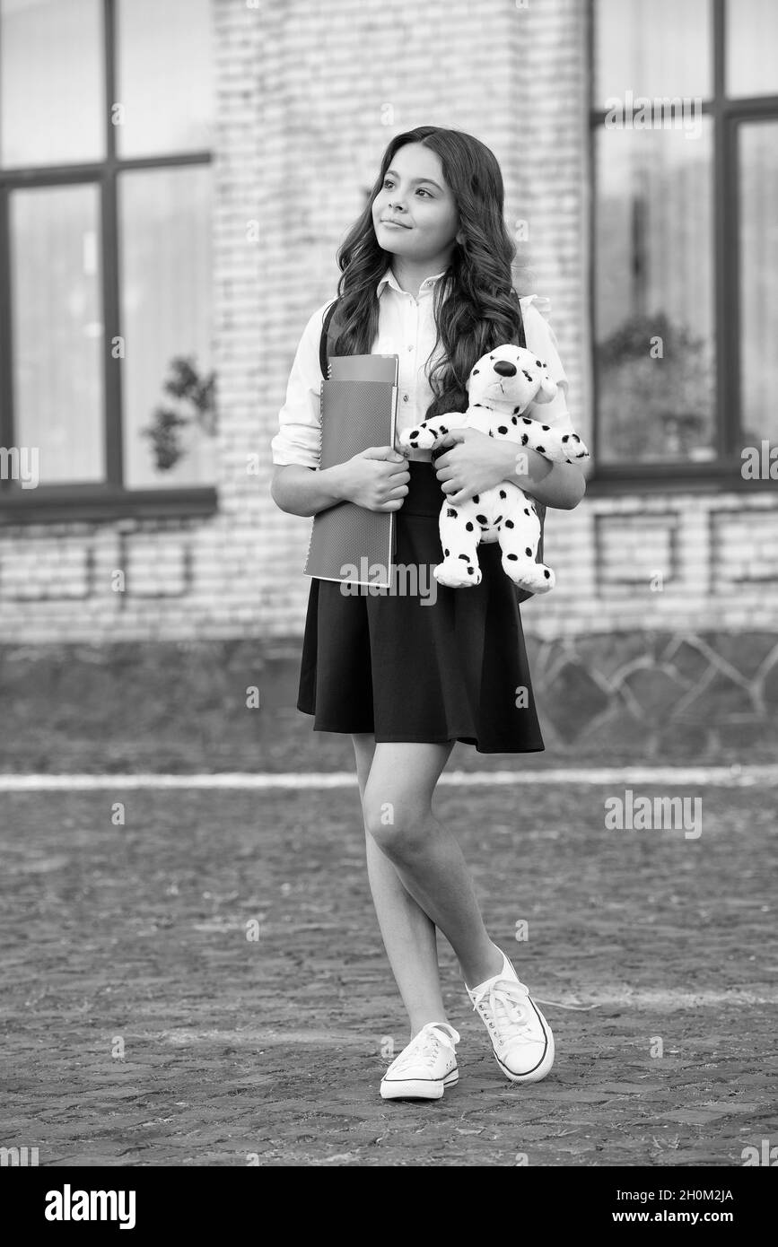 Better future through play. Little child hold books and toy dog outdoors. Black and white.Child development and learning. Preschool education. Playsch Stock Photo