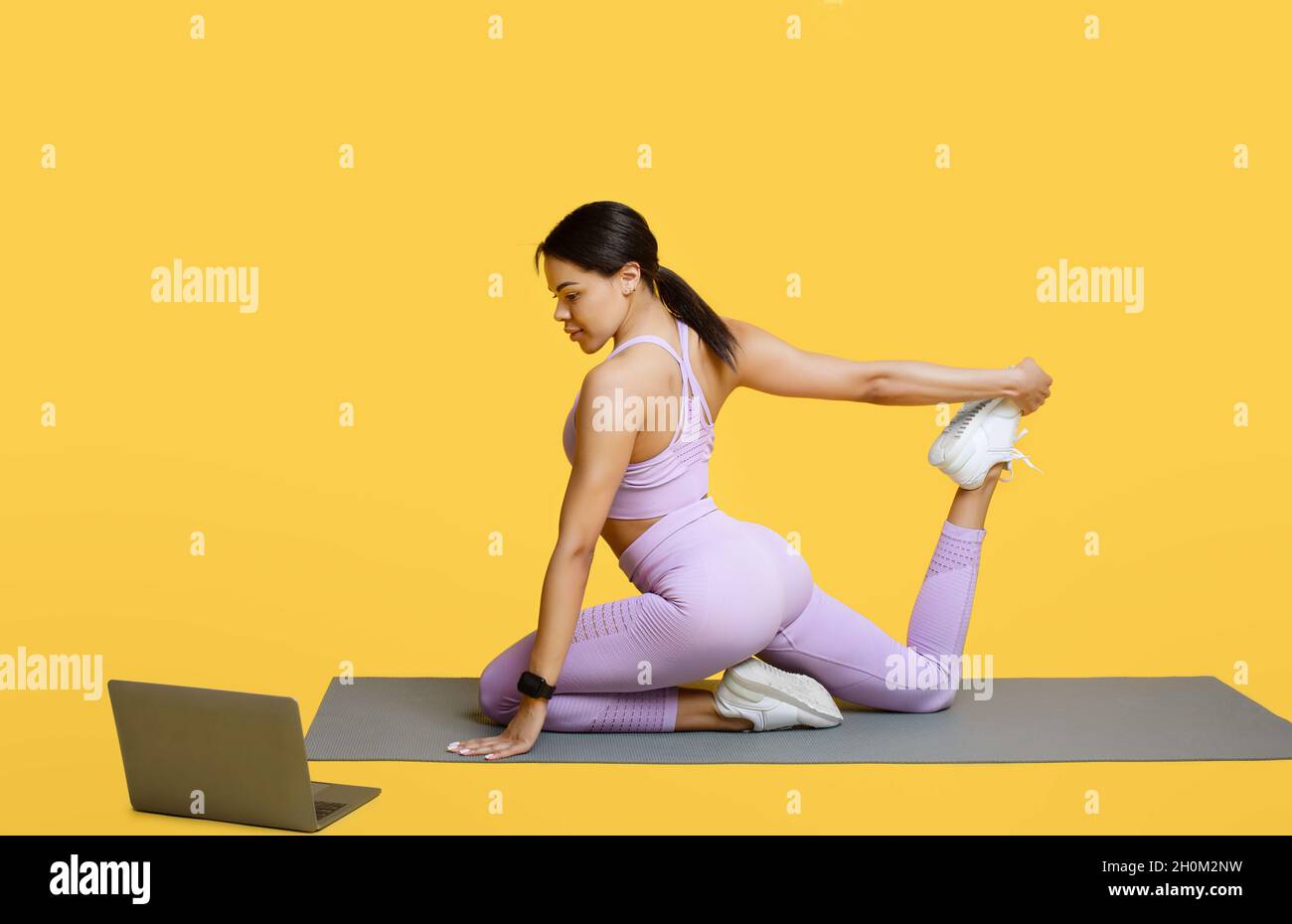 Fitness online. Young black woman stretching, sitting on yoga mat in ...