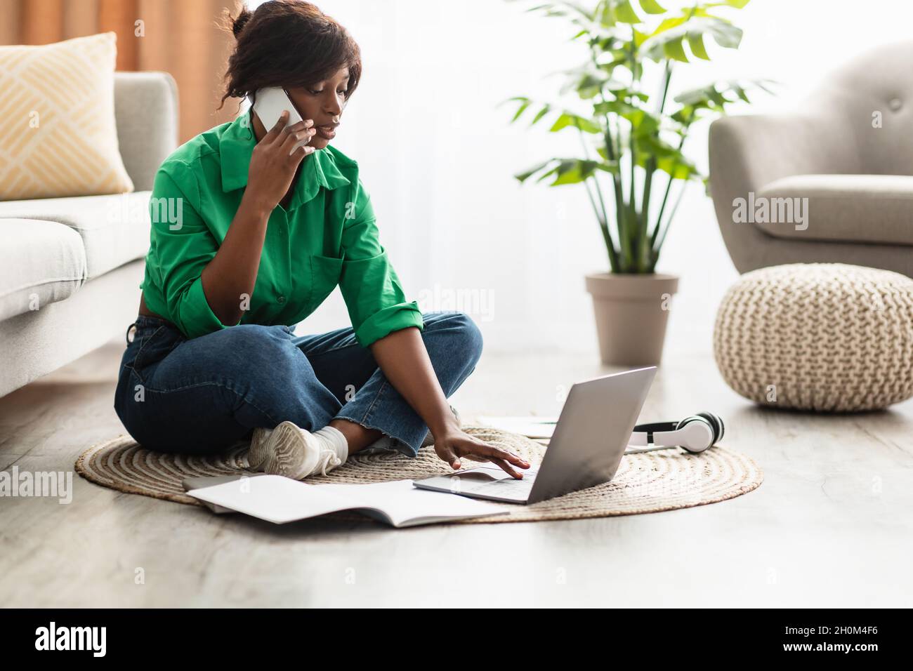 African American Woman Talking On Phone Using Laptop At Home Stock Photo