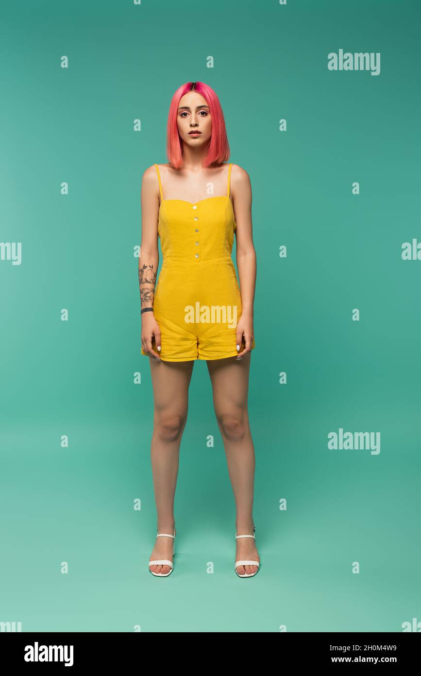 full length of young woman with pink dyed hair posing on turquoise Stock Photo