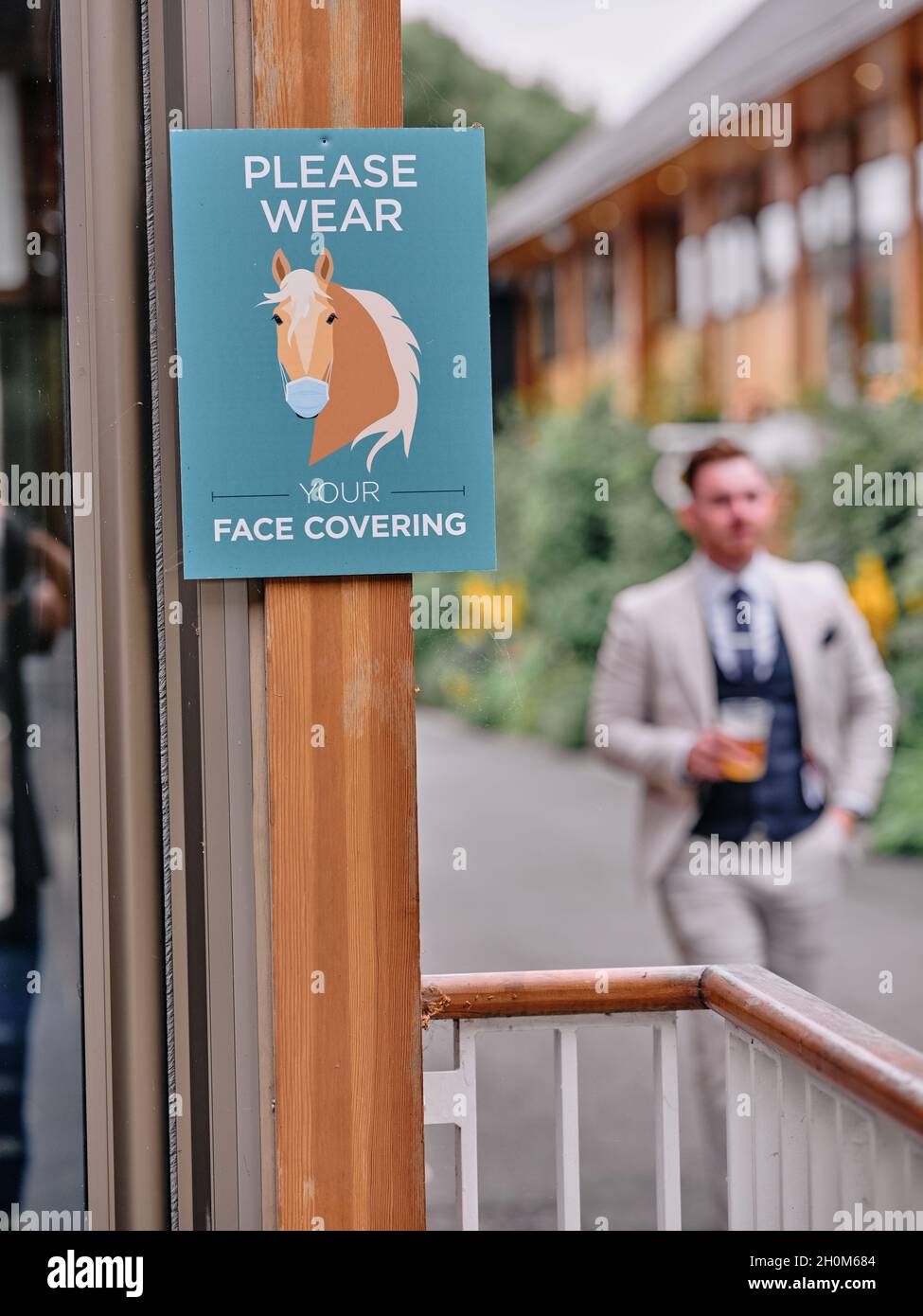 Covid face mask covering sign at an entrance to a day's horse racing at a racing event at York Racecourse York, Yorkshire, England UK 2021 Stock Photo