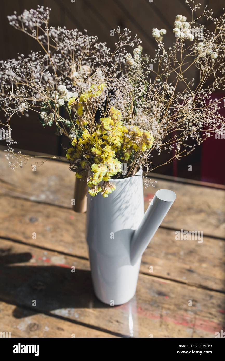 Rustic interior with a rough wooden table and flowers in a white vase ...