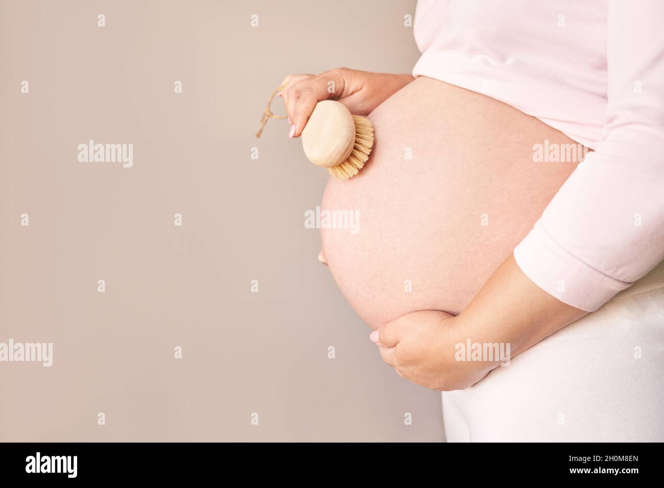 Pregnant skin care. Body brush routine. Woman belly peeling Stock Photo