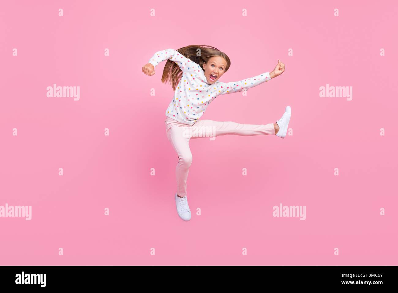 Photo of crazy karate little kid lady jump kick leg wear dotted pajama pants shoes isolated pink color background Stock Photo