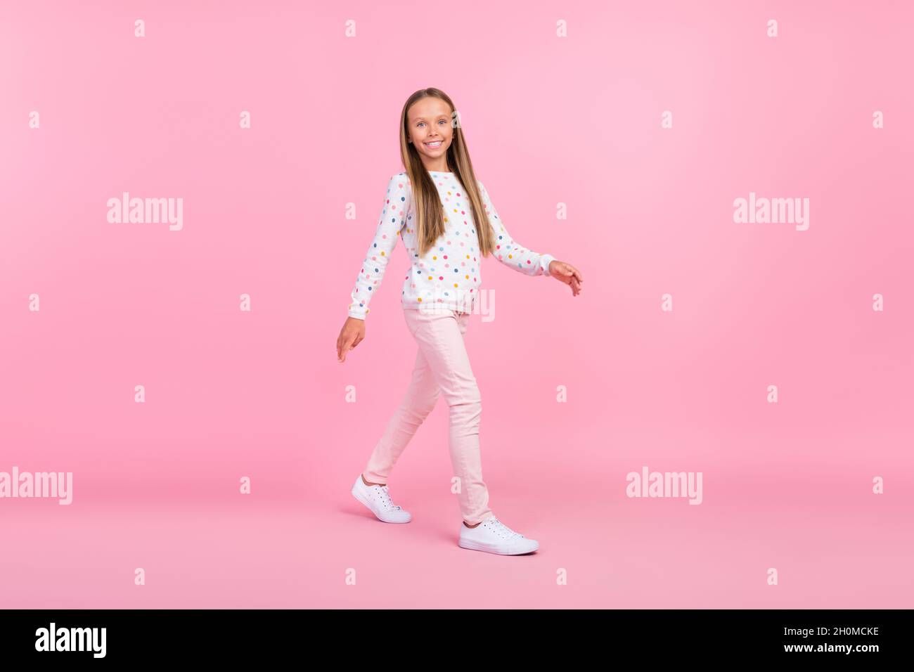 Photo of cheerful carefree little lady walk step street wear dotted shirt  isolated pink color background Stock Photo - Alamy