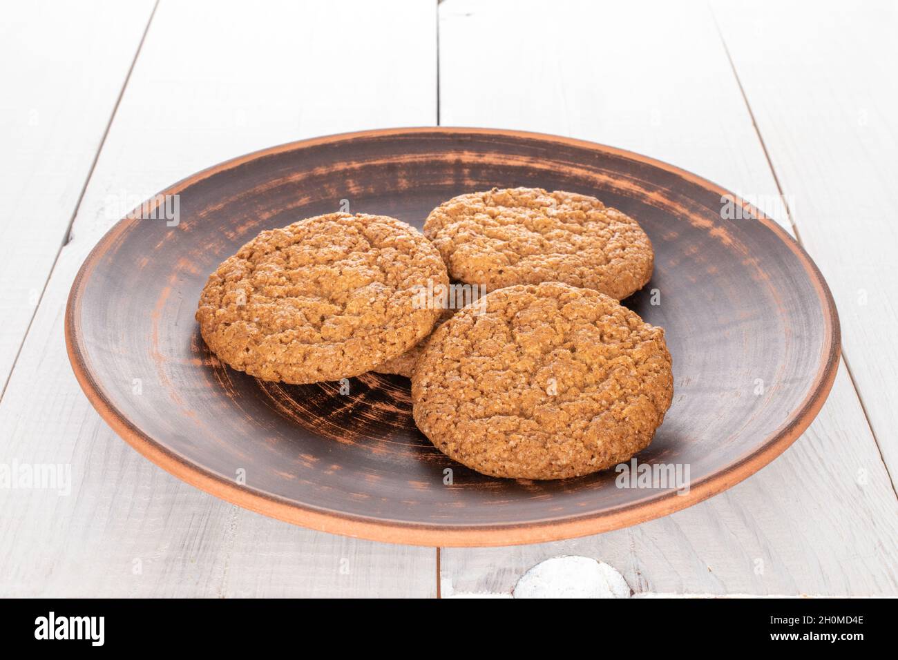 Several sweet oatmeal cookies with ceramic dishes, close-up, on a wooden table. Stock Photo