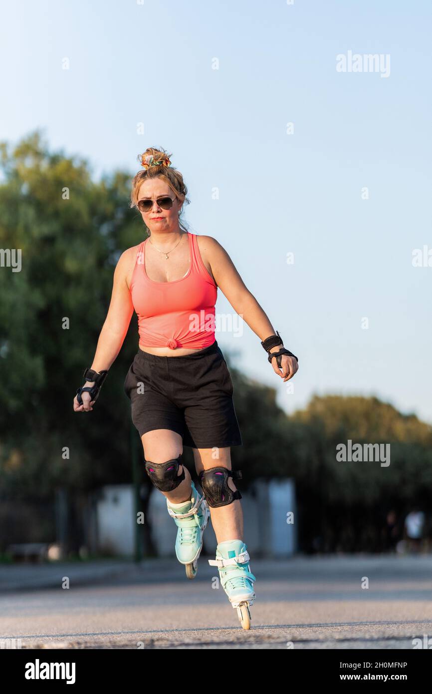 Woman with protective equipment skating with inline skate outdoors