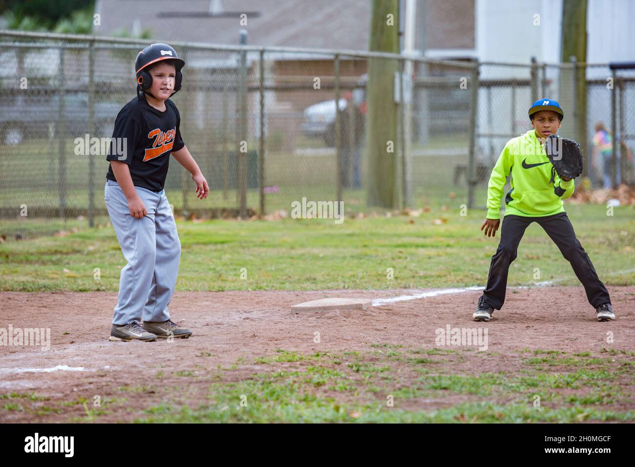 Young pre-teen male leading off at third base while playing baseball in uniform Stock Photo