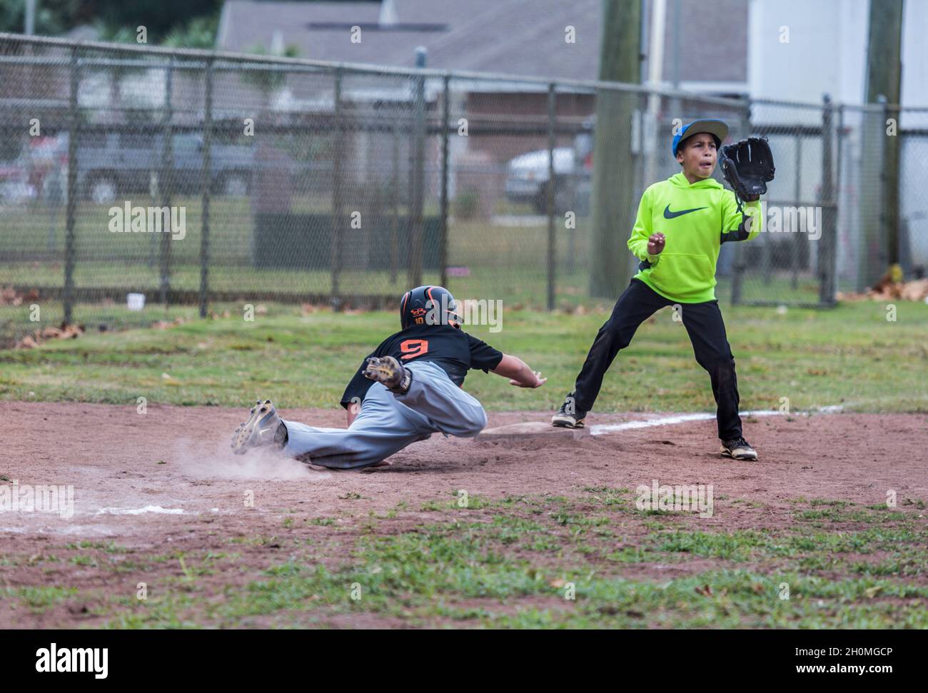 Young pre-teen male diving back to third base while playing baseball in uniform Stock Photo