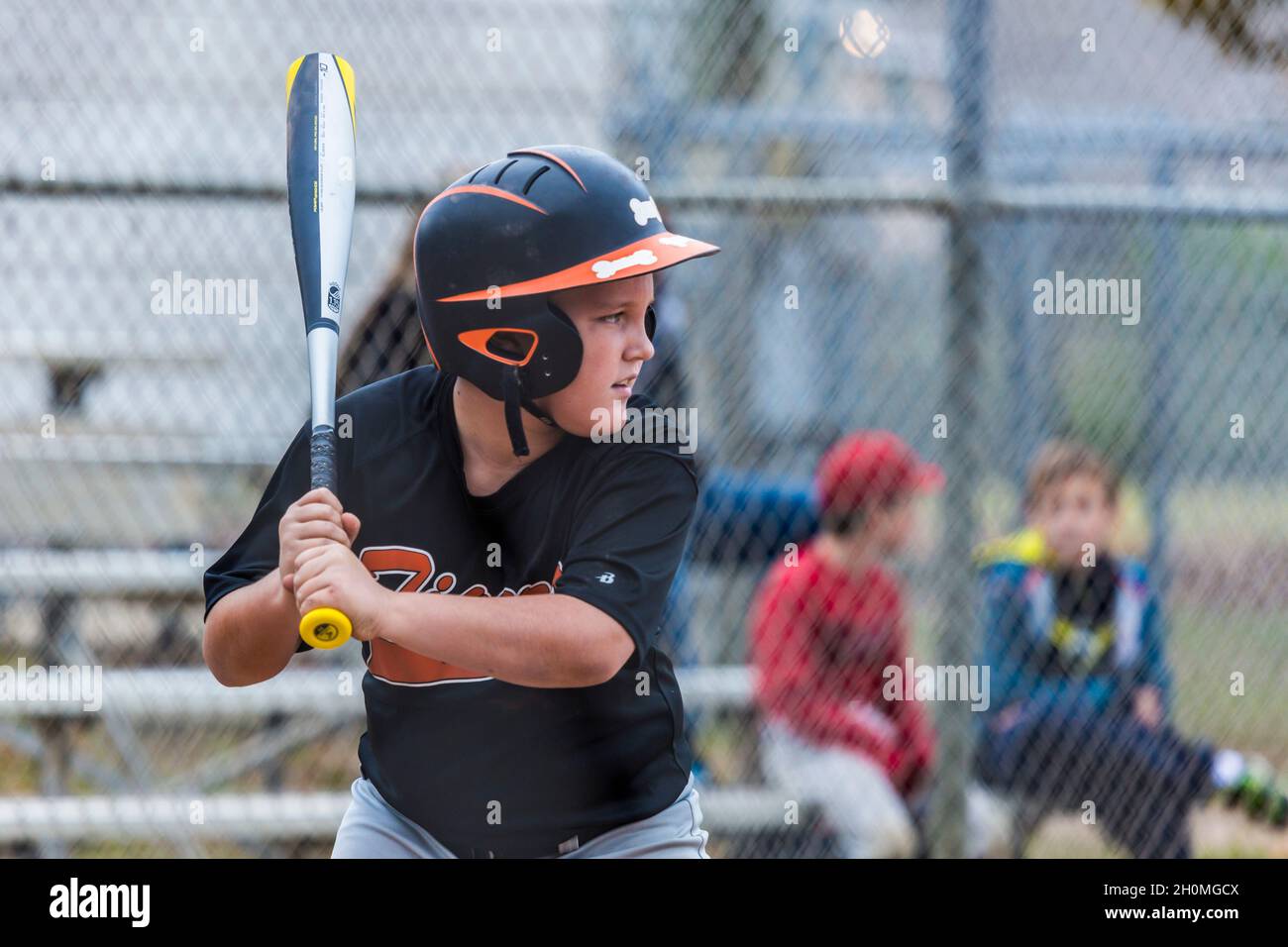 Young pre-teen male focusing on the pitched ball while playing baseball in uniform Stock Photo