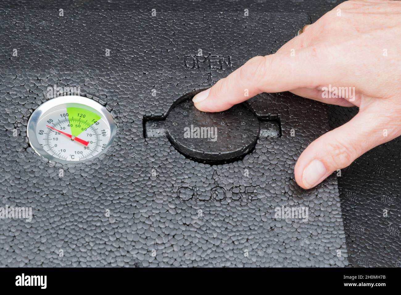 Adjusting the ventilation on top of a hot compost bin for composting