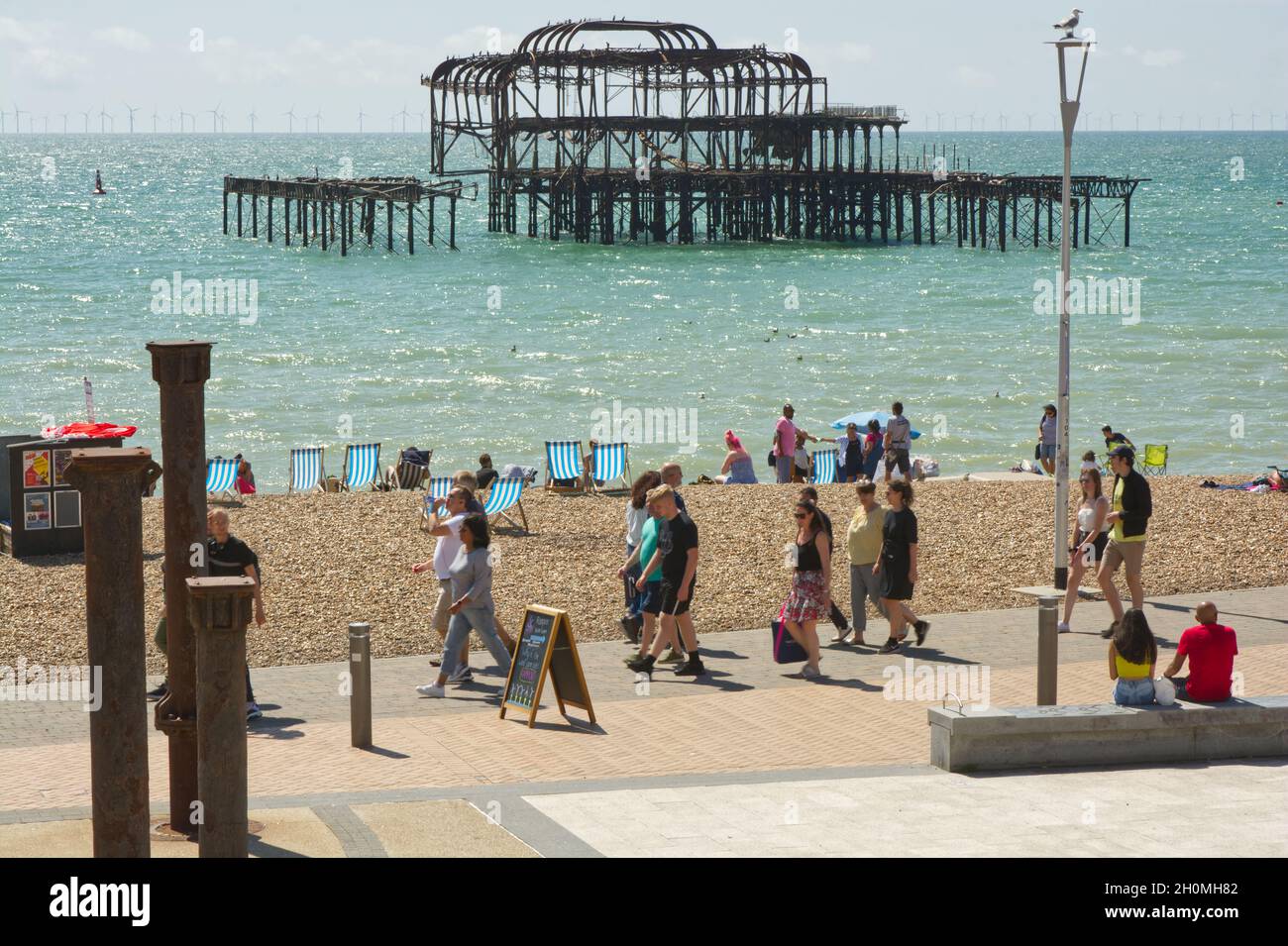 Beach and seafront promenade with old ruined West Pier at Brighton, East Sussex, England Stock Photo
