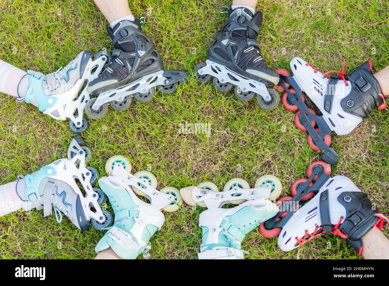 Cropped photo of people with inline skates together in the grass of a park Stock Photo