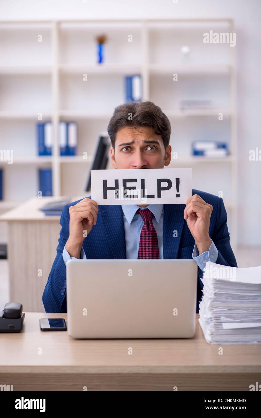 Young male employee and too much work in the office Stock Photo