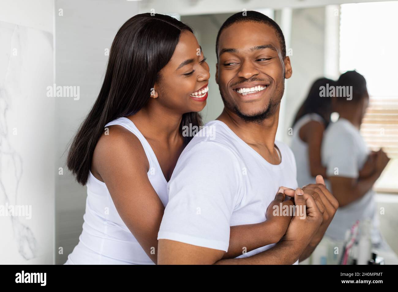 Portrait of happy young african american couple embracing near mirror ...