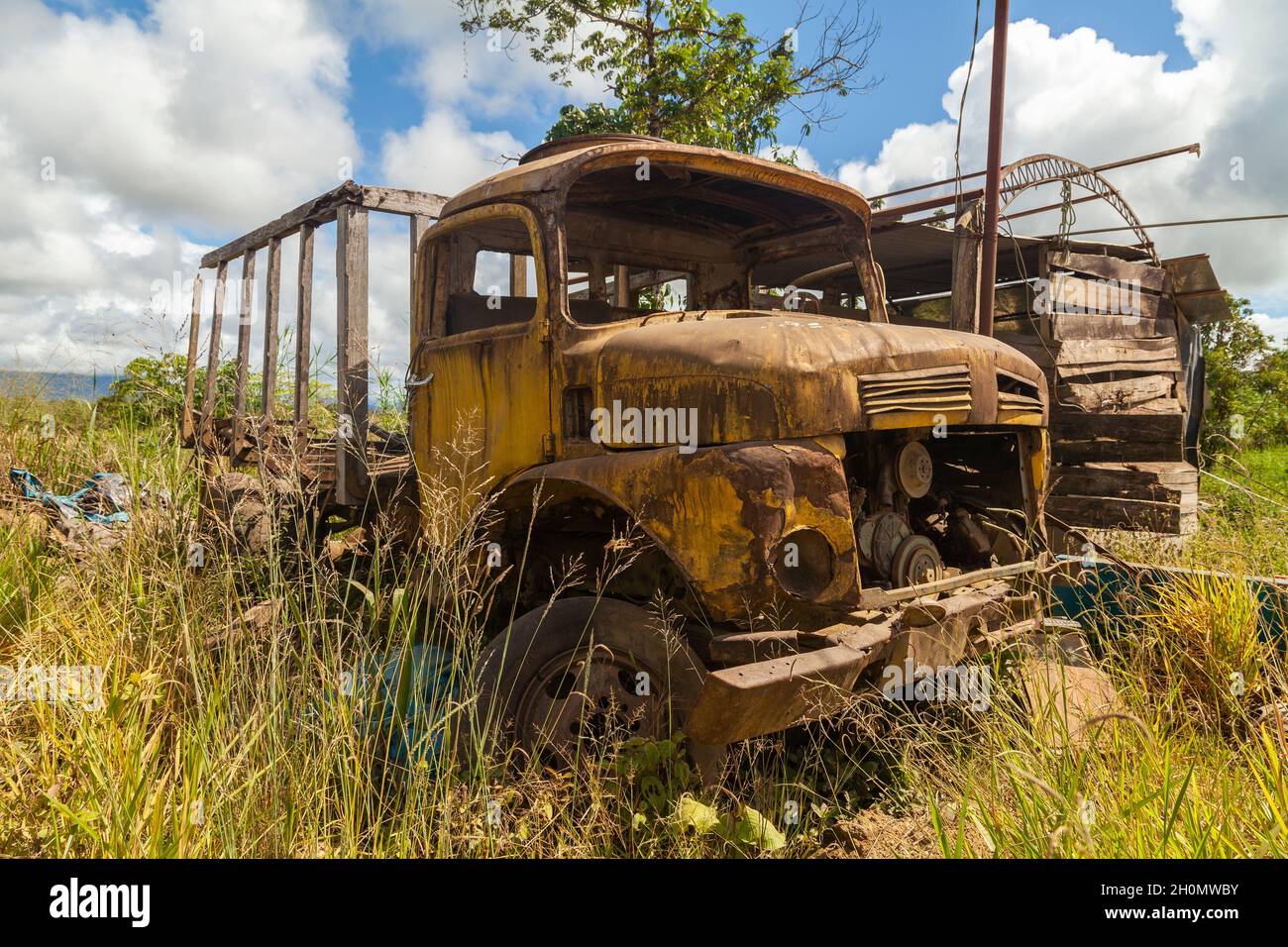Pilcopata, Peru - April 12, 2014: An old, rusty and abandoned yellow truck, engulfed by weeds, rests in the surroundings of Pilcopata Stock Photo