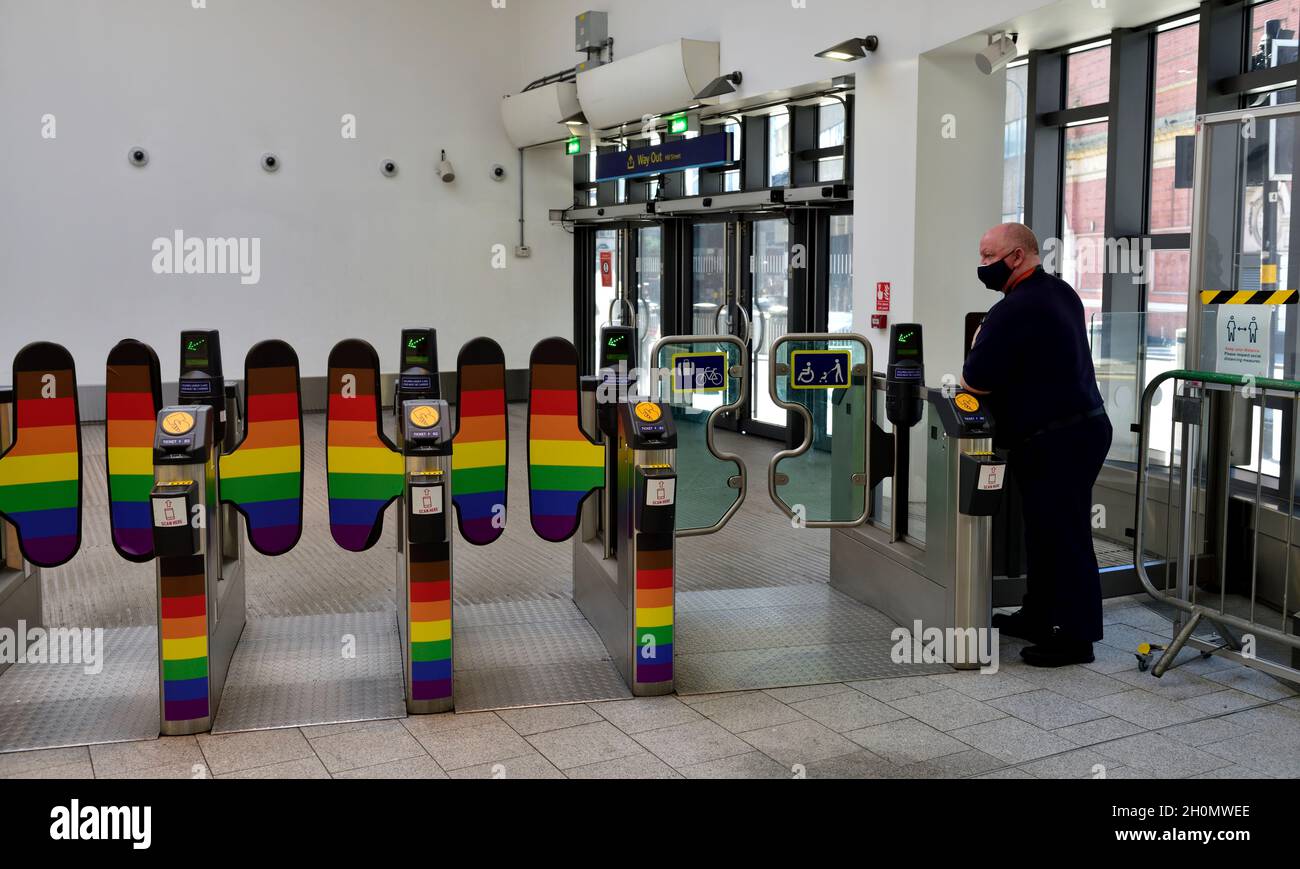 Rainbow coloured ticket barriers with ticket collector at Birmingham New Street train station, UK Stock Photo