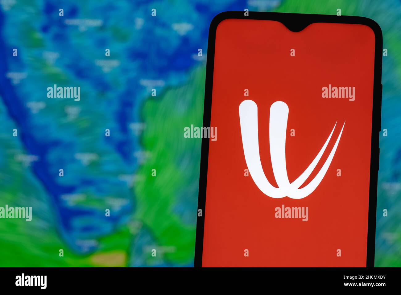 Windy is interactive weather forecasting service worldwide. Windy logo on smartphone screen. On the background of the weather forecast over India. Stock Photo