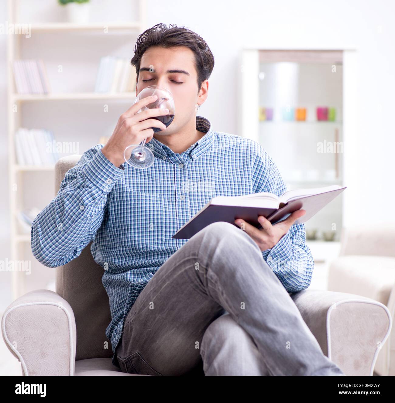 The young man drinking wine at home Stock Photo - Alamy