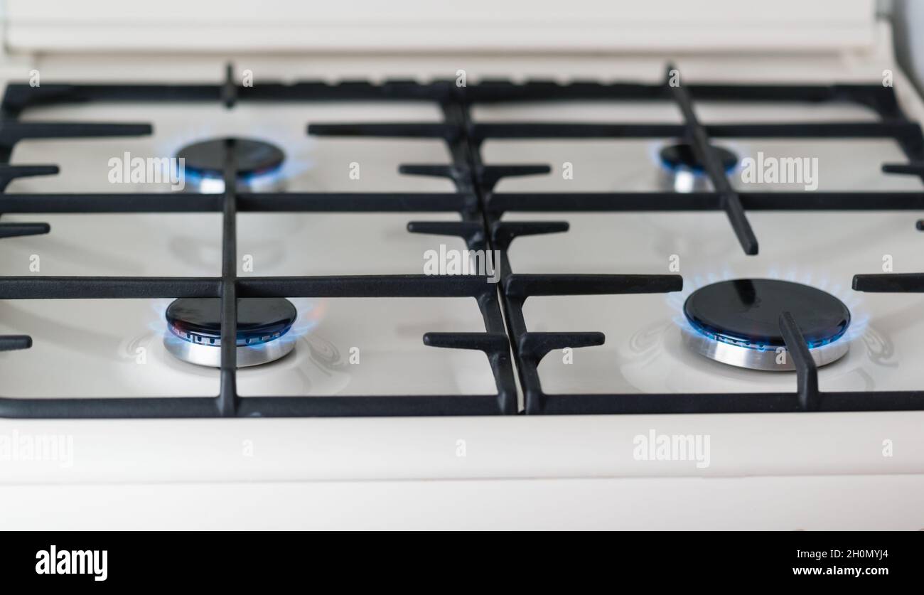 Closeup of a white enameled gas stove with black burners burning with