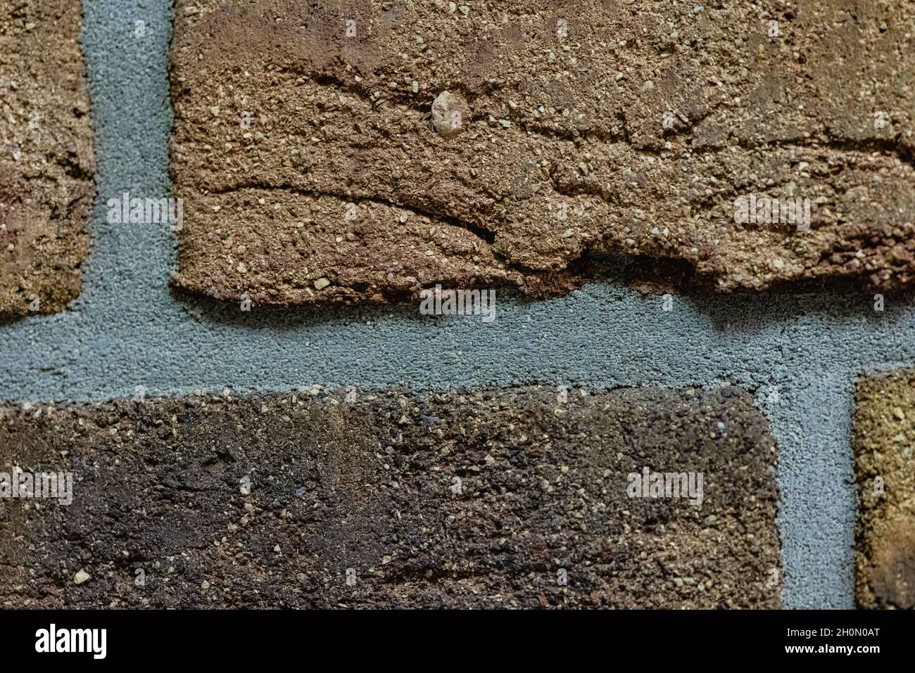 Close-up texture of a brown scratched brick wall with a gray seam Stock Photo