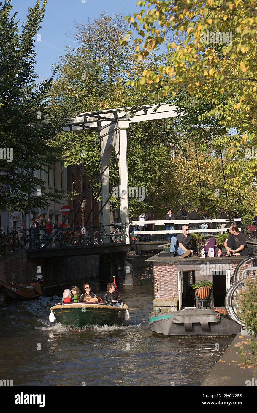 NETHERLANDS, NORTH HOLLAND, AMSTERDAM. LINGERING ON GROENBURGWAL CANAL AND TILT BRIDGE BEHIND Stock Photo