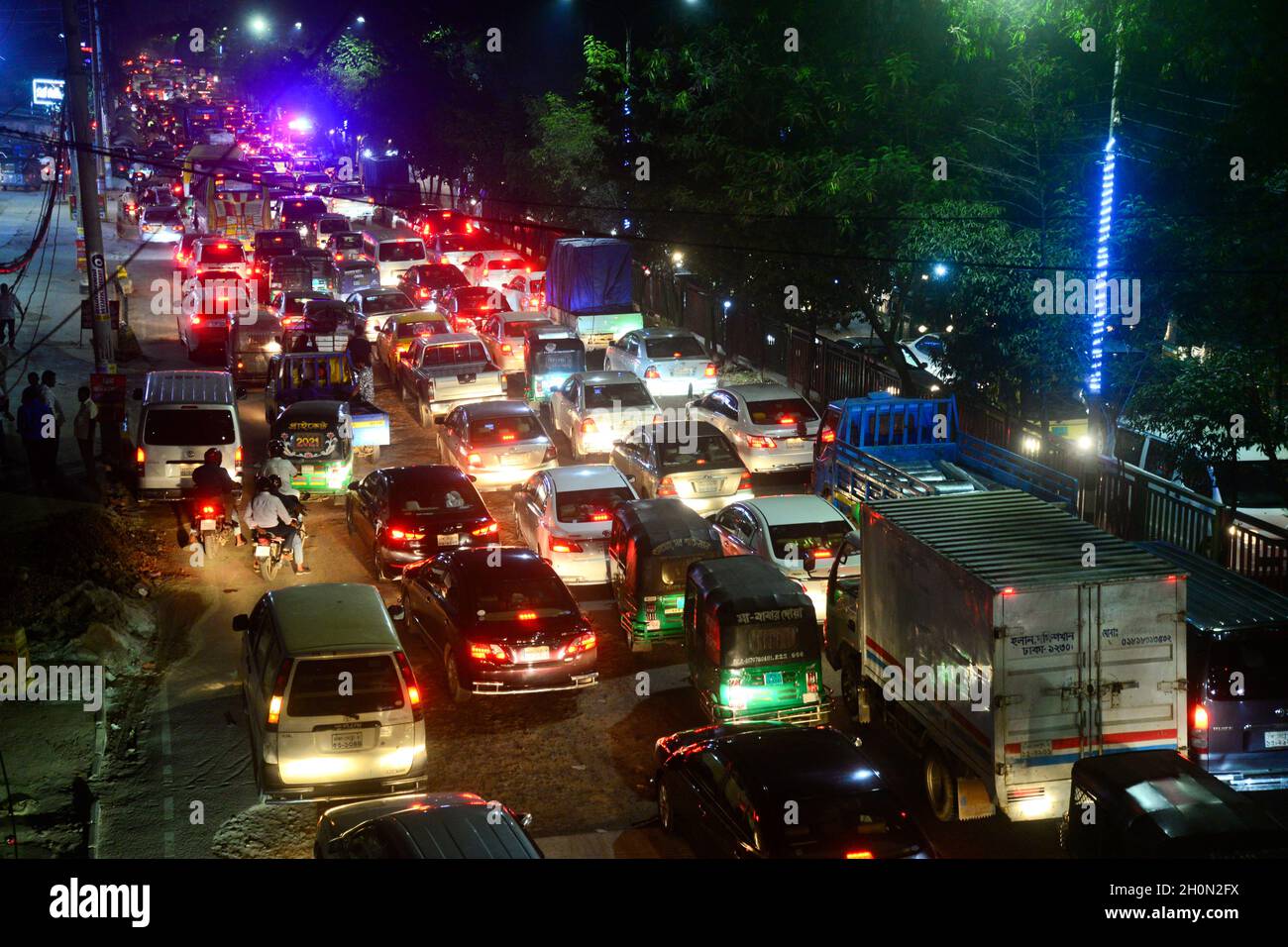 Commuters make their way through a traffic jam at night during Covid-19 Coronavirus pandemic in Dhaka, Bangladesh, on October 13, 2021.Last 10 years in Dhaka, average traffic speed has dropped from 21 km/hour to 7 km/hour, only slightly above the average walking speed. Congestion in Dhaka eats up 3.2 million working hours per day according to static reports. Stock Photo