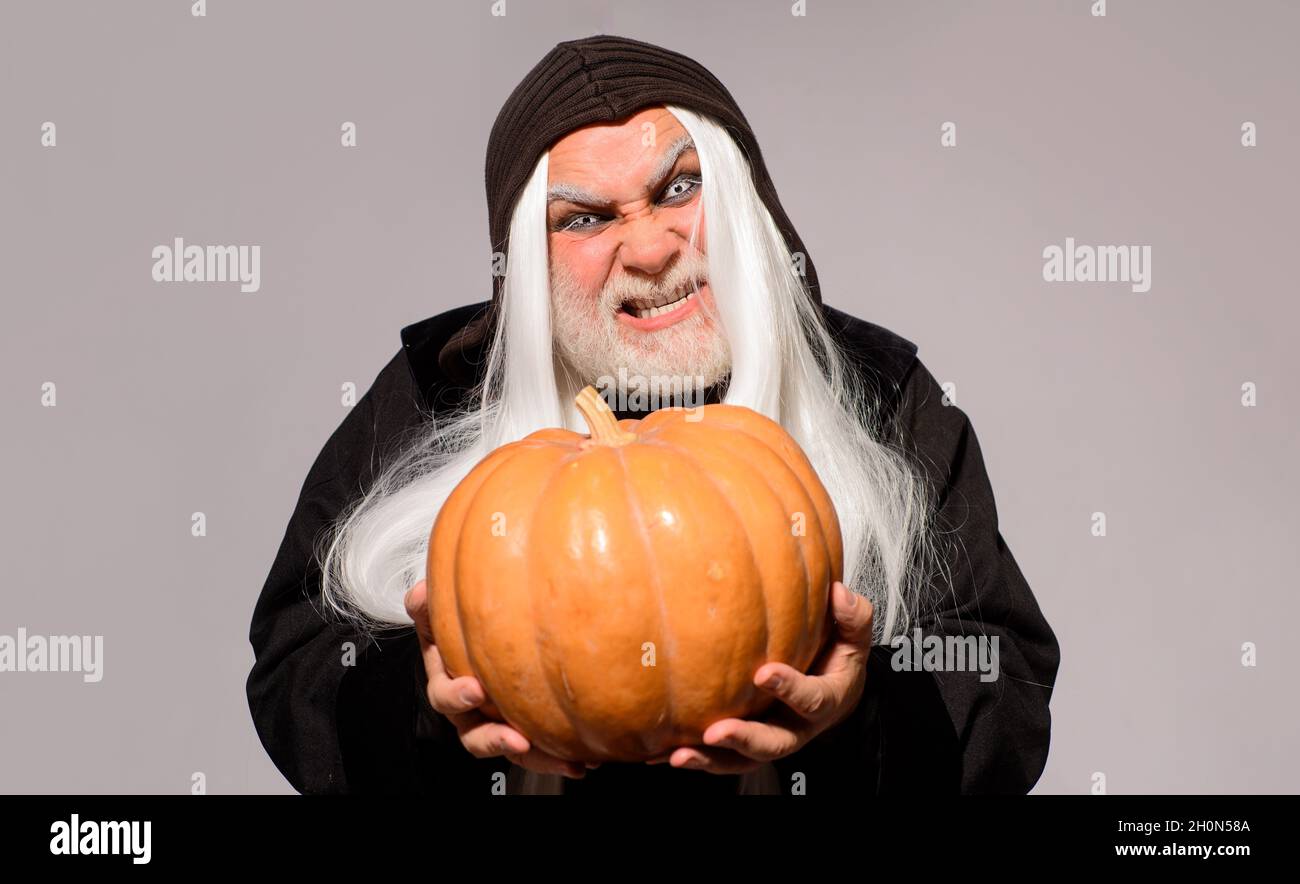 Evil wizard with orange pumpkin. Fantasy horror Halloween. Wicked Devil man with Jack-o-lantern. Angry Demon on Halloween night. Stock Photo