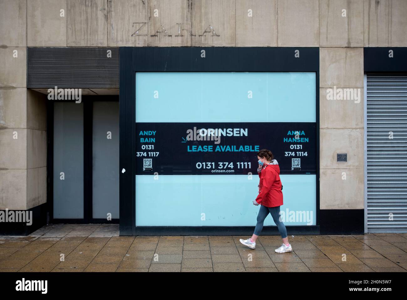Young woman walking by a closed Zara store on Princes Street having relocated to the new St James Centre, Edinburgh, Scotland, UK. Stock Photo
