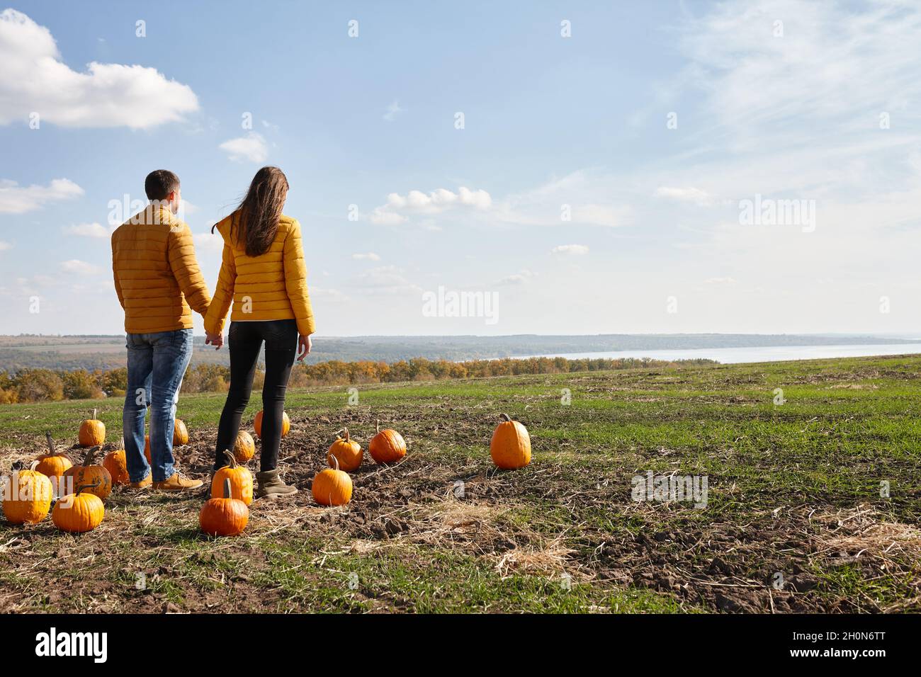 Young couple enjoying sunset in pumpkin patch field Stock Photo