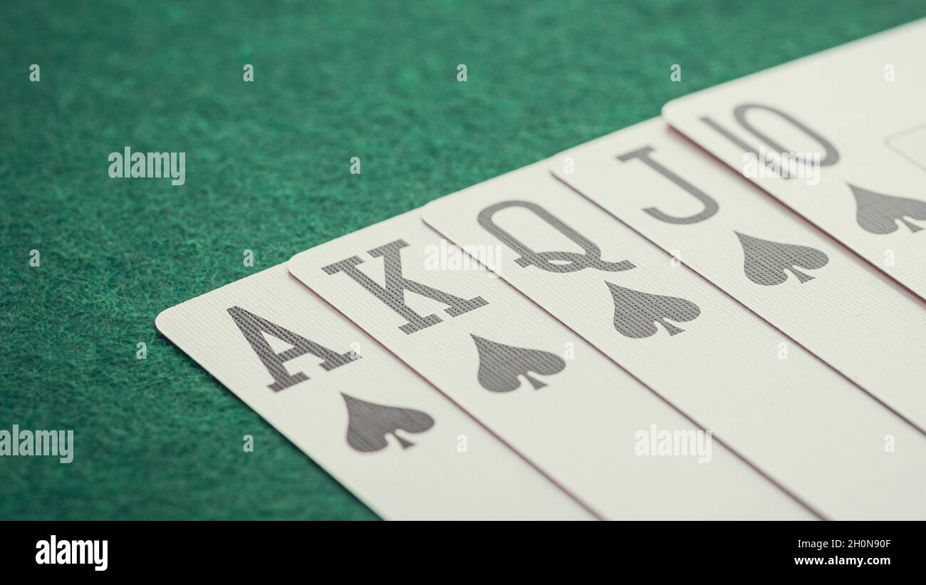 The combination of playing cards poker casino. Royal flush in suit of spades on green card table
