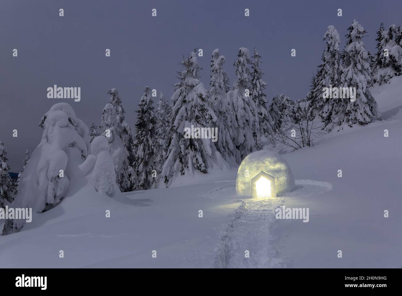 Night winter mountain landscapes. Igloo stands on the snowy lawn. House with light. Location place the Carpathian Mountains, Ukraine, Europe. Stock Photo