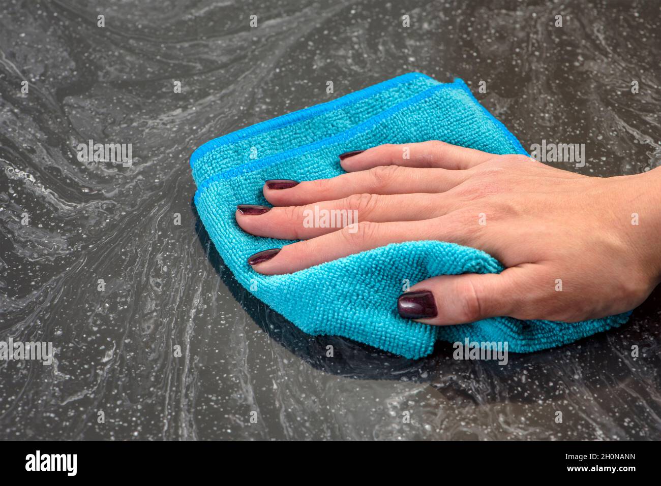 Cleaning the countertop. Caring for countertops in the kitchen or bathroom. Cleaning stone, marble or artificial stone countertops. Woman's hand wipes Stock Photo