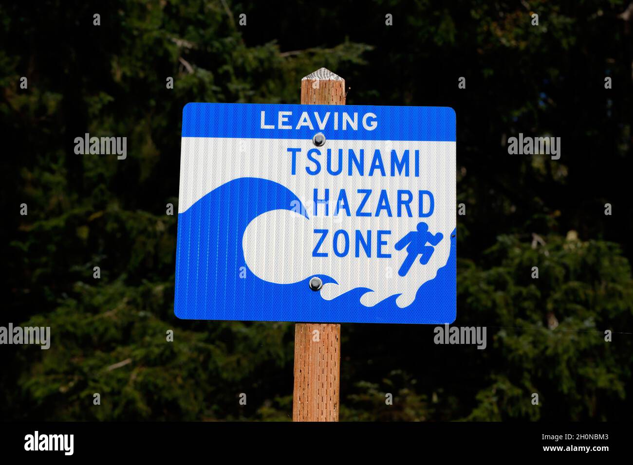 A blue information sign on a pole warns 'Leaving Tsunami Hazard Zone' Stock Photo