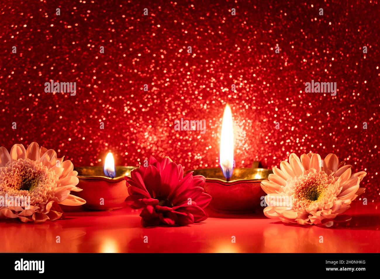 Happy Diwali. Burning diya oil lamps and flowers on red glittering background. Celebrating the traditional Indian festival of light. Copy space. Stock Photo