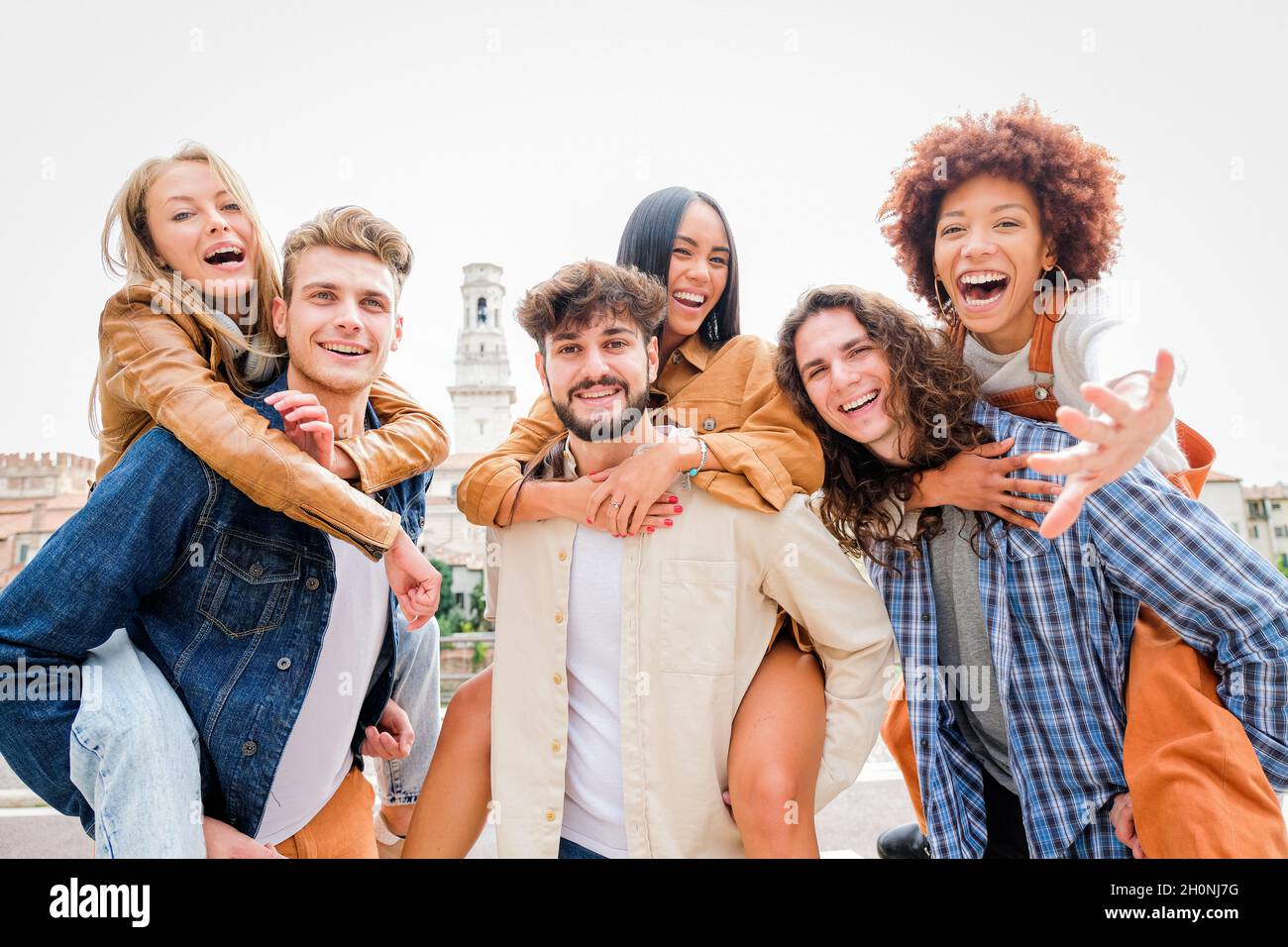 Young Friends having Fun Outdoors - Six students outdoors, men carrying two girls on their backs Stock Photo