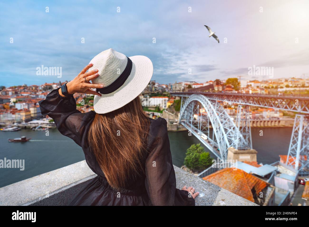 Young woman tourist enjoying beautiful view of Porto city and famous Dom Luis I Bridge at sunset. Summer holiday vacation in North Portugal. Stock Photo